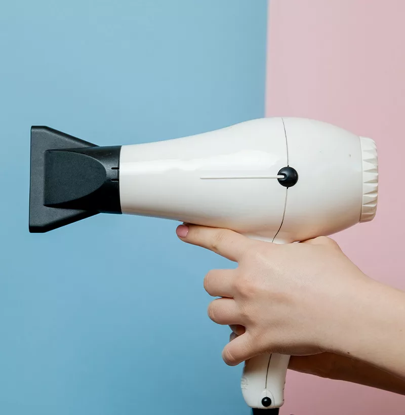 A person holding white hairdryer